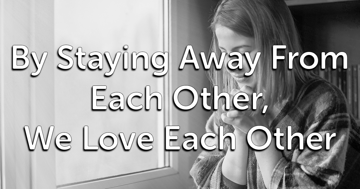 Black and white image of a person standing by a window, looking down and holding their hands close to their face. Large text superimposed over the image reads, "By Staying Away From Each Other, We Love Each Other.