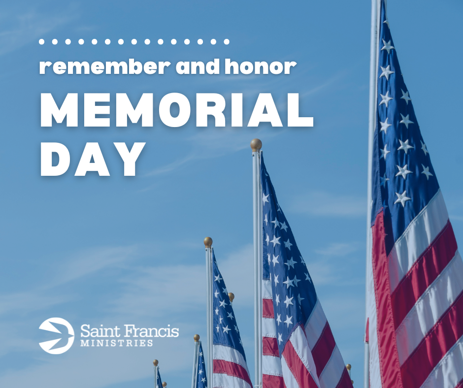 Image with a blue sky background featuring multiple American flags and the words "remember and honor MEMORIAL DAY" in bold white letters. The bottom left corner has the logo and text "Saint Francis Ministries".