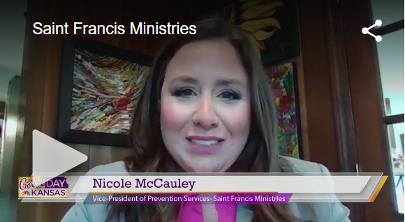 A woman with long brown hair and pink lipstick is on screen, labeled as Nicole McCauley, Vice-President of Prevention Services at Saint Francis Ministries. She is wearing a blazer. The screen also displays "Good Day Kansas" in the corner with a play button.